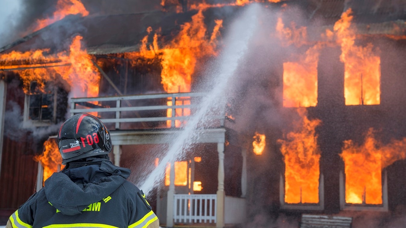 Trabajo de Bombero: bombero extinguiendo el fuego de una vivienda